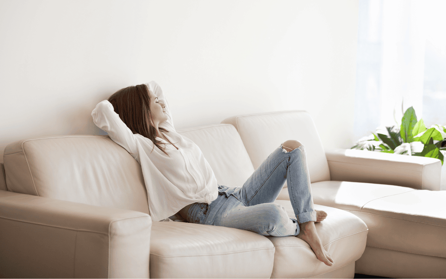 Mujer joven disfrutando de un momento de relax en el sofá de su hogar.