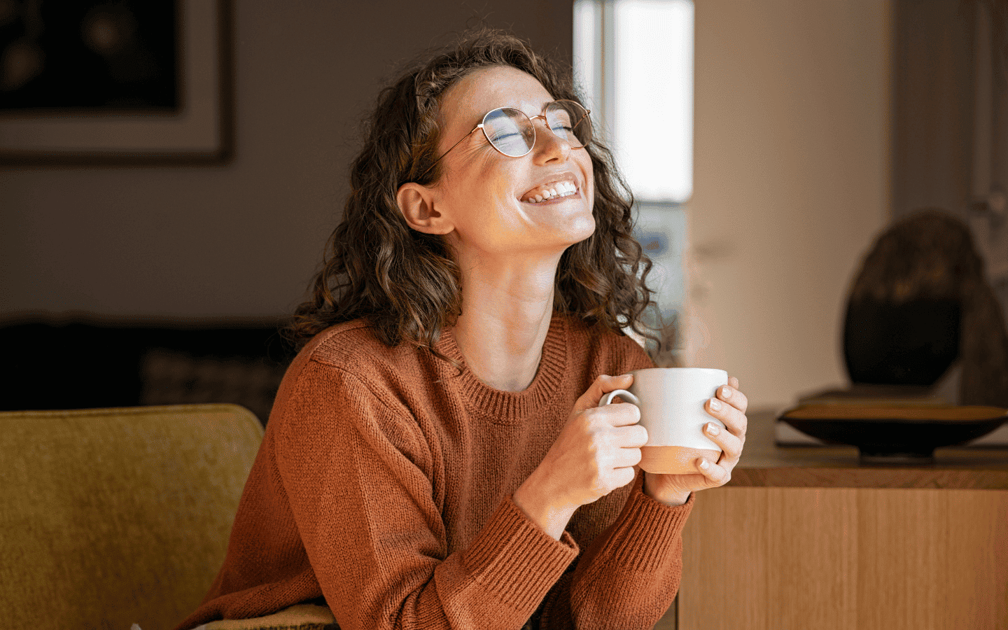 Mujer joven disfrutando de un momento de relax tomando una tasa de te en su hogar.